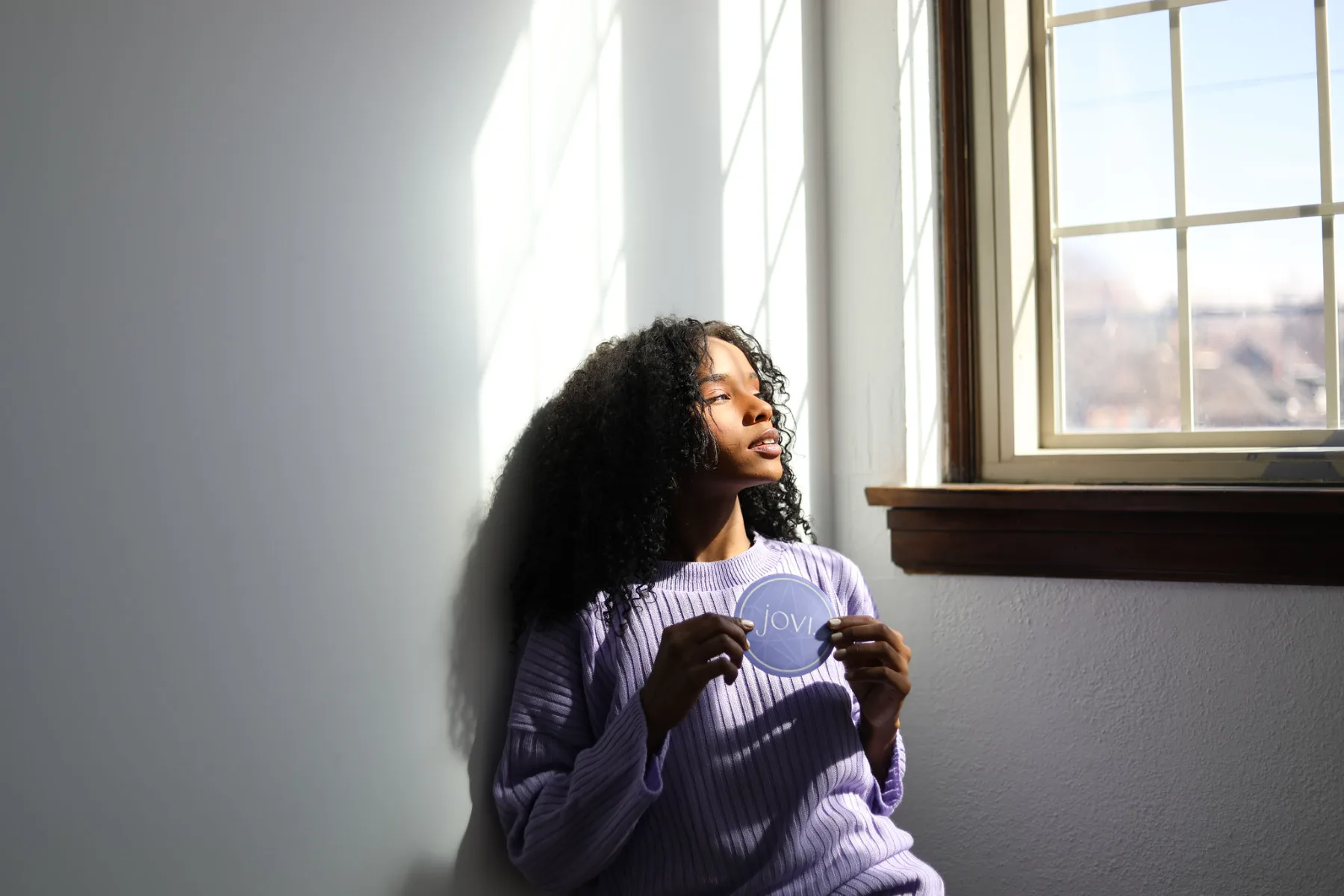 Model in lilac knit holding a Jovi coaster